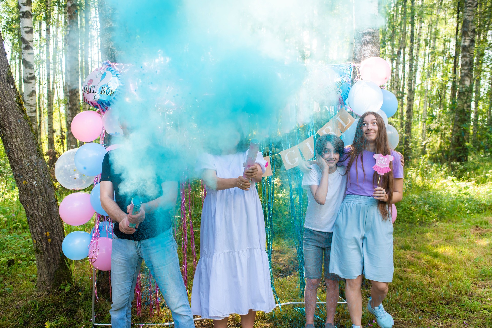 A family with two children at a gender reveal party finds out if their baby is a boy or a girl. Blue smoke or holly paint from a party popper. It's a boy!